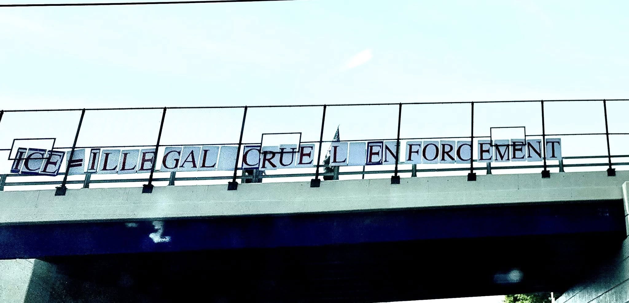 a bridge bridage shows the message ice equals illegal cruelty enforcement